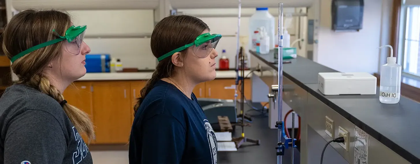 Two women in a chemistry lab conducting experiements and analyzing data.